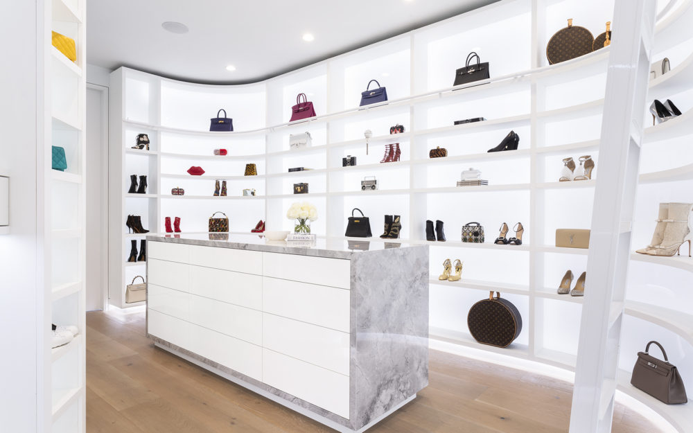 A very bright, back-lit walk-in closet fro shoes and purses.