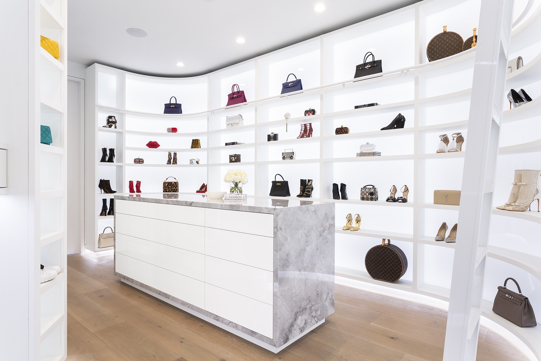 A very bright, back-lit walk-in closet fro shoes and purses.